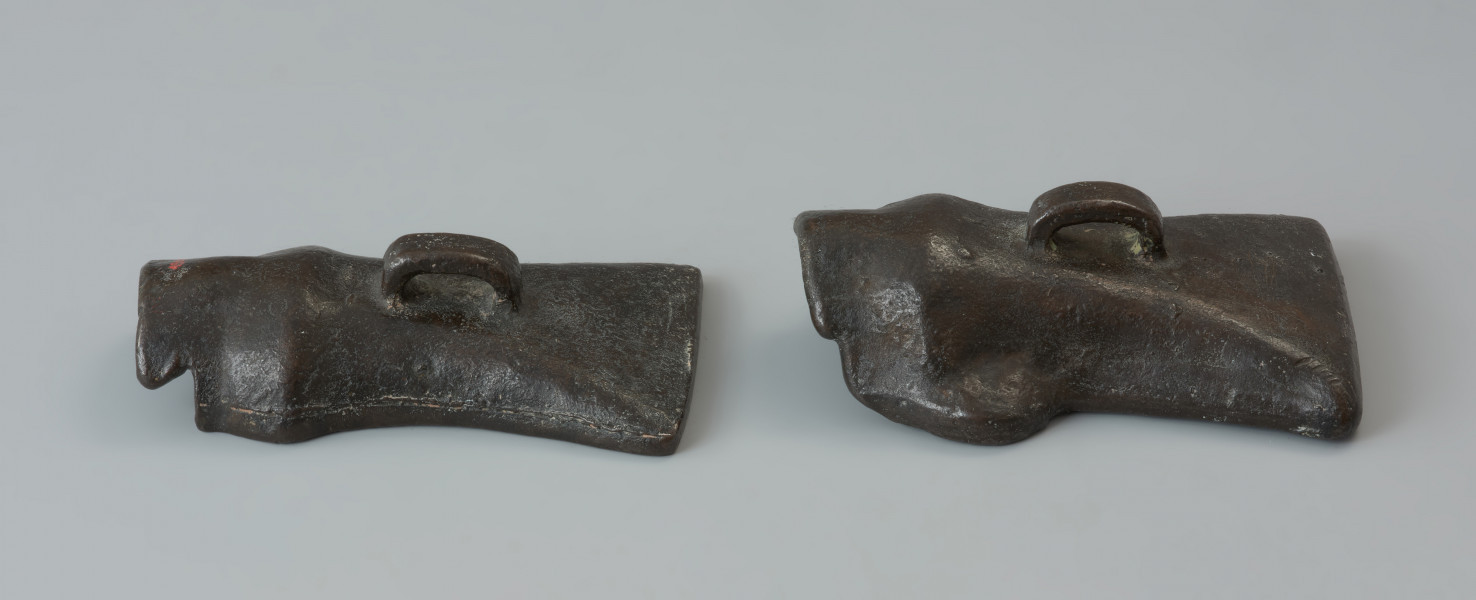 forma odlewnicza; forma muszlowata - Ujęcie obu części formy z góry. Dwuelementowa forma odlewnicza z brązu o brunatnozielonkawej barwie, której kształt wewnętrzny tworzy negatyw siekierki z tulejką i uszkiem. Połówki formy są do siebie dokładnie dopasowane, przy czym jedna zagłębia się lekko w drugiej. Wewnątrz ich korpusów znajdują się niewielkie wypustki w formie czopów, formujących uszko siekierki przy odlewaniu. Na ściankach zewnętrznych każdej połówki znajduje się uchwyt w postaci taśmowatego uszka. Powierzchnie te nie są gładkie a nieco porowate.