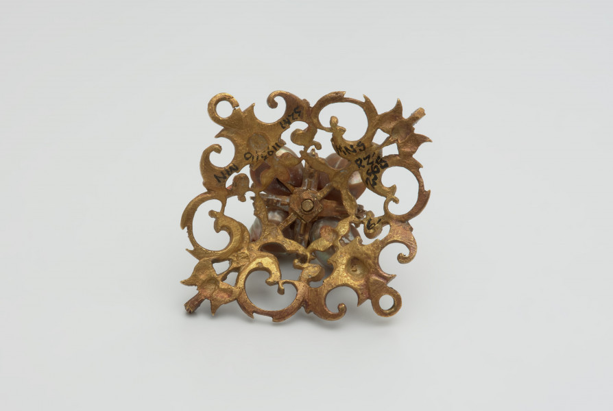 biżuteria, ozdoby - Ujęcie z tyłu. Ażurowy klejnot z kołpaka z diamentem i czterema perłami, zdobiony barwną emalią.