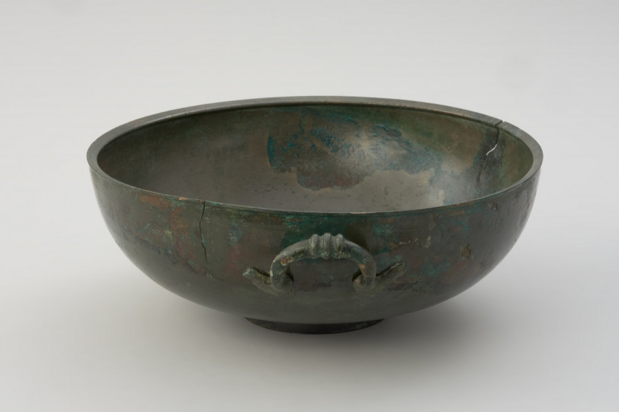 misa z brązu - Ujęcie z lewego boku. Rzymska misa z brązu na stopce, zaopatrzona w parę przeciwstawnych uch z trzema guzami pośrodku.