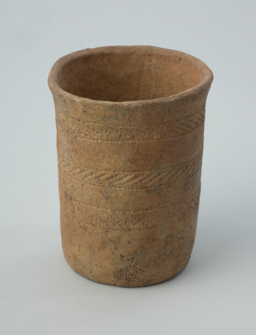 Naczynie gliniane - Ujęcie z przodu; Puchar o formie moździerzowatej z niemal pionowymi ściankami i lekko rozchylonym wylewem, zdobiony w części środkowej i górnej trzema dookolnymi pasmami ukośnych odcisków zamkniętych pomiędzy pojedynczymi liniami poziomymi. Ornament wykonany jest pięciozębnym narzędziem (grzebieniem).