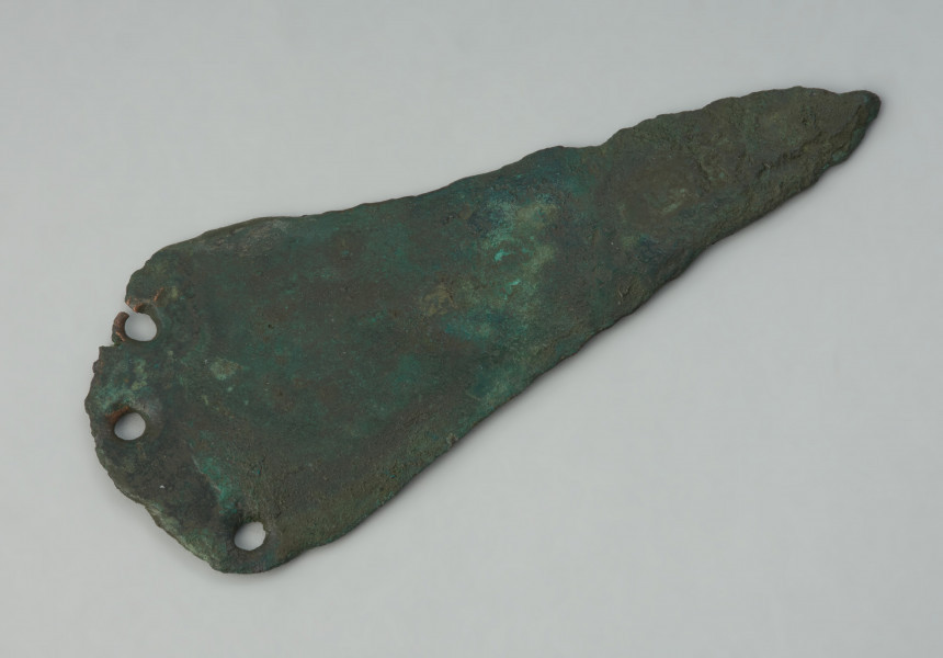 ostrze sztyletu z półkolistym zakończeniem, wariant Mierczyce - Ujęcie z góry przodu siekierki skosem do góry. Trójkątna głownia sztyletu z brązu, pokryta zielona patyną, ma półkoliście uformowaną płytkę do przytwierdzania rekojeści, w której znajdują się trzy otwory na nity. Krawędzie ostrza są zniszczone.