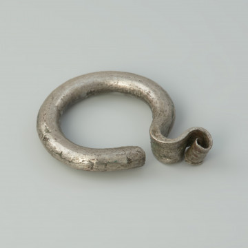 kabłączek skroniowy, biżuteria - Ujęcie z przodu skosem w prawą stronę. Kabłączek skroniowy wykonany z srebrnego drutu o okrągłym przekroju z esowatym uszkiem.