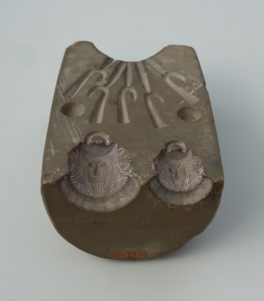 Forma odlewnicza - Ujęcie w pionie brodatymi twarzami w dół.  Jedna część dwudzielnej, kamiennej formy odlewniczej z wizerunkami brodatych twarzy. Wykonano ją ze steatytu zwanego też słoninowcem lub kamieniem mydlanym, który jest miękki i łatwy w obróbce. Zdaniem odkrywców służyć miała do odlewania haczyków do wędek i ciężarków do sieci. Dzisiaj najczęściej uważa się, że jest to forma do odlewu uchwytów niewielkich zawieszek, tzw. osełkowatych lub dzwoneczków. Uwagę zwracają przede wszystkim zróżnicowane wielkościowo wyobrażenia męskich twarzy o migdałowatym kształcie, z dużymi oczami i obfitym zarostem. Po wykonaniu odlewu uzyskiwano przedmiot z wizerunkiem czterech twarzy, uważany za okucie niewielkiej osełki. Forma jest starannie wykonana i nie ma żadnych śladów użytkowania.