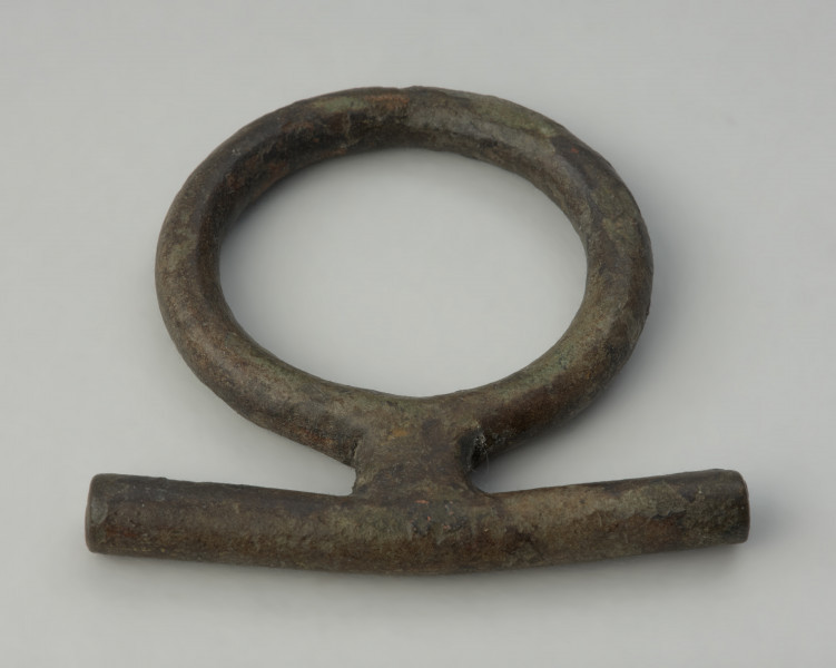 zawieszka , pobocznica , element uździenicy - Ujęcie z góry tyłu. Brązowy krępulec z przetyczką, złożony z kółka i beleczki.