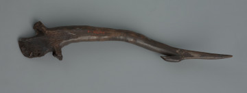 harpun ornamentowany z jednym zadziorem - ujęcie z tyłu; Narzędzie pokryte jest pięcioma seriami ukośnych i poprzecznych nacięć. W części środkowej harpuna tworzą ułożony pasmowo ornament kratki, pod zadziorem i przy podstawie przyjmują formę poprzecznych linii. Przy ostrzu powyżej zadziora widoczne jest złamanie, które zostało sklejone. Barwa zabytku ściemniała na skutek długotrwałego przebywania w osadach rzecznych.