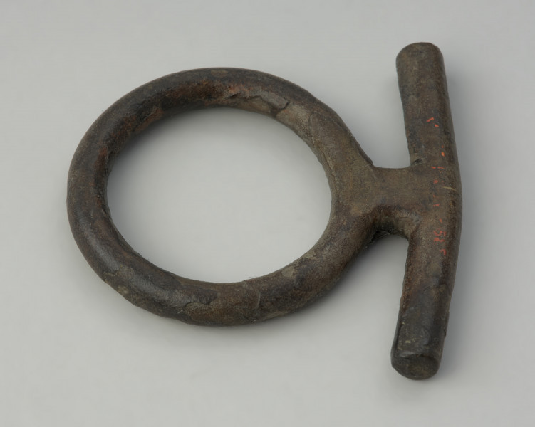 zawieszka , pobocznica , element uździenicy - Ujęcie z góry prawego boku. Brązowy krępulec z przetyczką, złożony z kółka i beleczki.