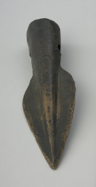 Grot oszczepu - Ujęcie z góry w pionie przodu grotu. Brązowy grot oszczepu ma smukłą formę oraz wąski liść. Na tulejce znajdują się dwa otwory na nity.