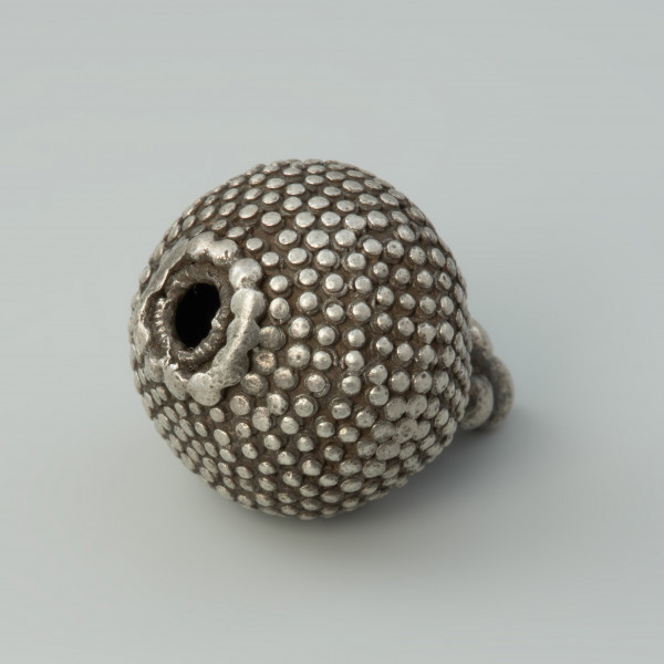 guz, biżuteria, ozdoba - Ujęcie tyłu skosem w prawą stronę w poziomie. Guz srebrny okrągłego kształtu zdobiony granulacją.