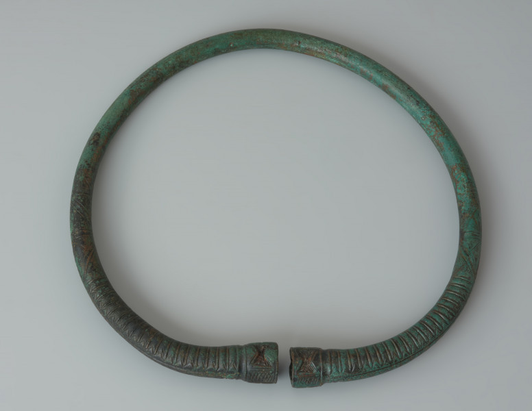 Naszyjnik z pogrubionymi zakończeniami wykonany z brązu - Ujęcie z dołu. Naszyjnik z pogrubionymi zakończeniami wykonany z brązu. Ornament krzyża na zakończeniach nosi ślady czerwonej emalii.