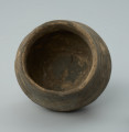 Jasnobrunatne naczynie gliniane o niskiej, przysadzistej formie - Ujęcie z góry i z tyłu. Jasnobrunatne naczynie gliniane o niskiej, przysadzistej formie.