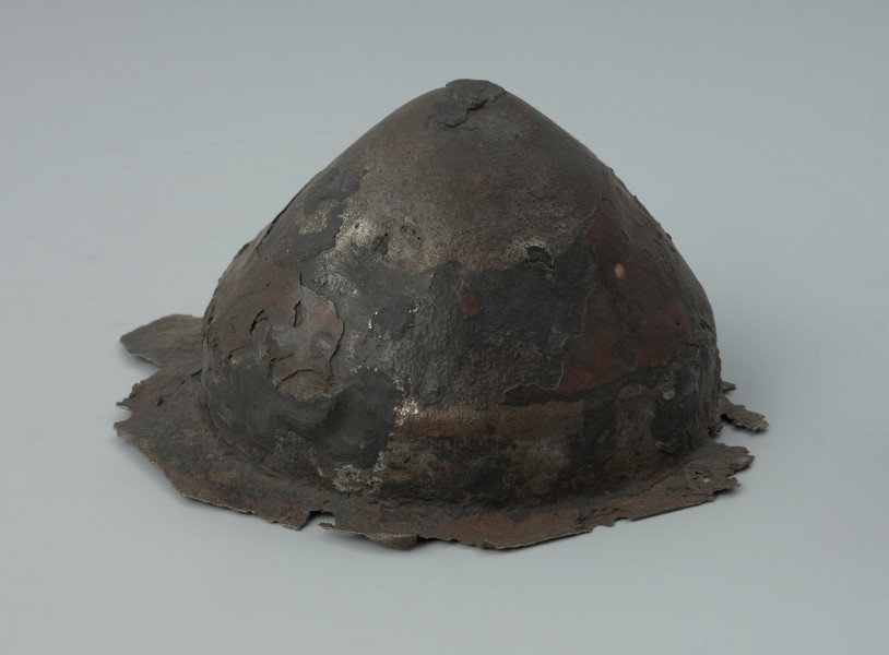 Żelazne umbo ze zniszczonym brzegiem. - Ujęcie z prawej strony. Żelazne umbo ze zniszczonym brzegiem.