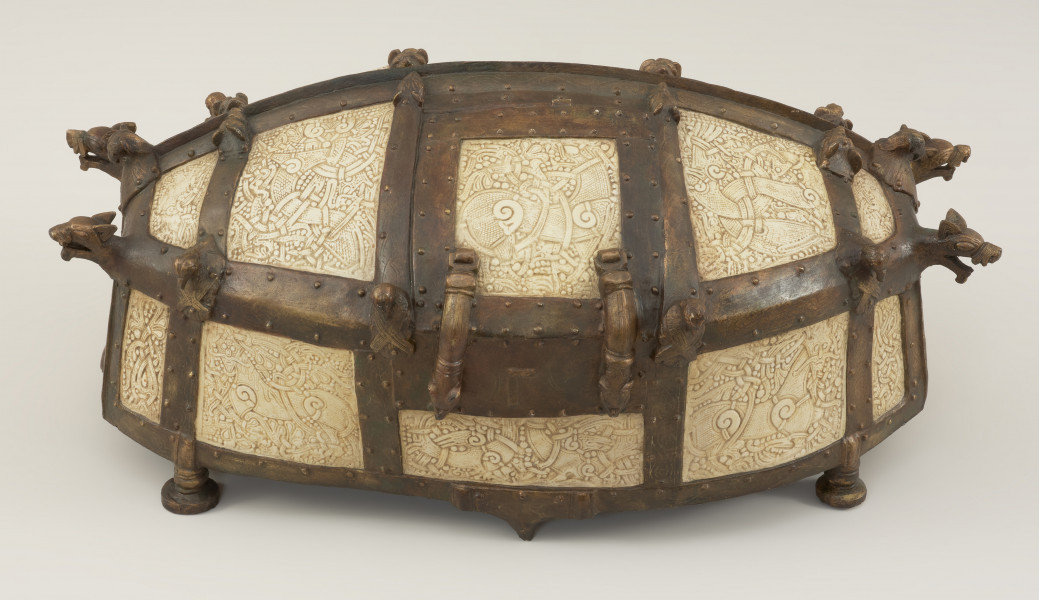 relikwiarz św. Korduli - Ujęcie z przodu skosem do góry. Owalna szkatuła wykonana z 22 płytek z poroża łosia zdobionych w skandynawskim stylu Mammen, którego głównym motywem był element poskręcanych bestii w towarzystwie wątków roślinnych, stosowany od połowy X do połowy XI wieku. Płytki połączono ze sobą za pomocą pozłacanej miedzianej taśmy, której zwieńczenia mają postać smoczych łbów. Dno relikwiarza wykonano z drewna dębowego, a stało ono na sześciu brązowych nóżkach.