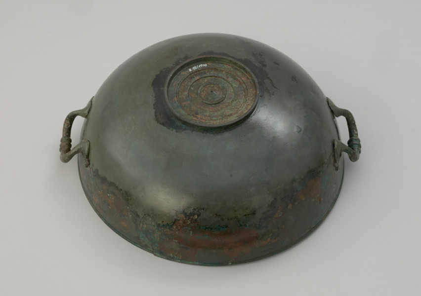 misa z brązu - Ujęcie spodu z góry. Rzymska misa z brązu na stopce, zaopatrzona w parę przeciwstawnych uch z trzema guzami pośrodku.