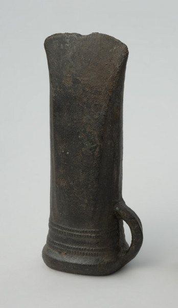 topór, siekiera - Ujęcie praweog boku w pionie. Siekierka brązowa z tulejką i dużym uszkiem, dekorowana żeberkowaniem i karbami przy wylocie tulejki.