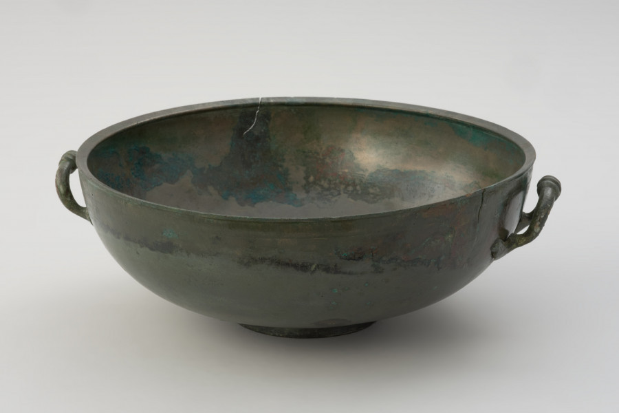 misa z brązu - Ujęcie z tyłu. Rzymska misa z brązu na stopce, zaopatrzona w parę przeciwstawnych uch z trzema guzami pośrodku.