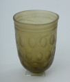 Naczynie szklane (pucharek) - Ujęcie z tyłu. Naczynie szklane (pucharek) grubościenne koloru jasnozielonego. Szkło jest przezroczyste.
