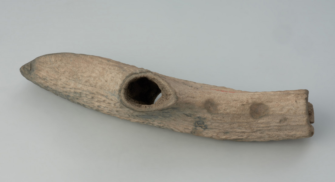 narzędzie, topór - Ujęcie z boku; Topór T-kształtny wykonany ze środkowej części tyki poroża jeleniowatych, z otworem na trzonek do rękojeści w miejscu opieraka odciętego w odległości 2,5-3 cm od tyki. Ostrze ucięte jednostronnie, równolegle do otworu. Obuch ścięty poprzecznie z wydrążoną substancją gąbczastą do głębokości 3 cm. Powierzchnia naturalna, korowa, przy ostrzu, od dołu ślad po podwójnym nacięciu