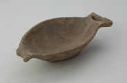 naczynie - Ujęcie z przodu skosem w lewą stronę. Płytka miseczka o oryginalnej formie, przypominającej kształtem rybę. Powierzchnia naczynia jest niezbyt starannie gładzona, barwa w tonacji szaro-brunatnej.