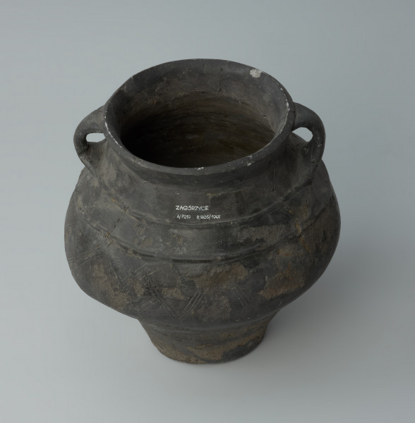 Dwuuche naczynie - Ujęcie z tyłu i z góry. Dwuuche naczynie o gładkiej powierzchni barwy ciemnobrunatnej, miejscami czarnej.