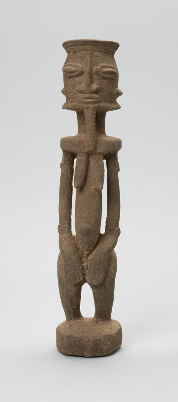 rzeźbiona figura - Ujęcie z przodu. Drewniana, rzeźbiona postać, z zaznaczonymi jednocześnie cechami płciowymi męskimi i żeńskimi. Wyodrębnione cechy męskie to broda, żeńskie: piersi.