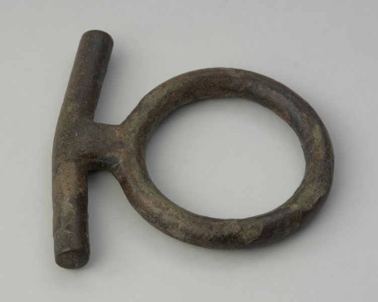 zawieszka , pobocznica , element uździenicy - Ujęcie z góry prawego boku. Brązowy krępulec z przetyczką, złożony z kółka i beleczki.