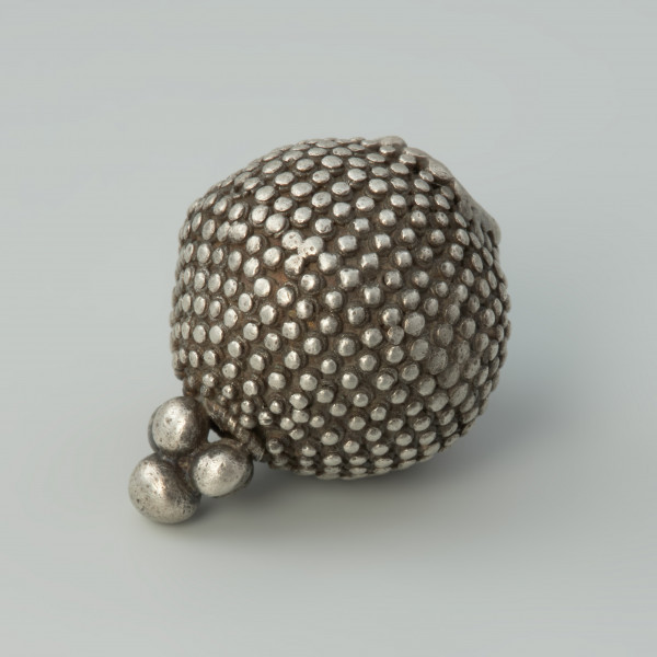 guz, biżuteria, ozdoba - Ujęcie skosem w prawą stronę w poziomie. Guz srebrny okrągłego kształtu zdobiony granulacją.