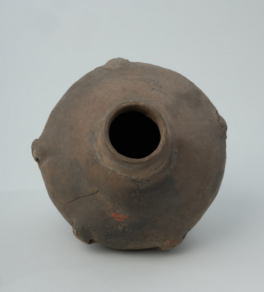 Naczynie gliniane - Ujęcie z góry; Amfora, zapewne o cylindrycznej szyjce (rekonstrukcja) i dwustożkowatym brzuścu, z pięcioma uchami na załomie, niezdobiona. Z prawej strony przy szyjce widoczne pęknięcie.