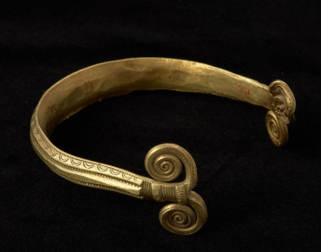biżuteria; ozdoba ciała - Ujęcie prawej strony naamiennika. Wygiety w literę U, złoty naramiennik zakończony wolutami, zdobiony na kabłąku motywami łuków i linii prostych.