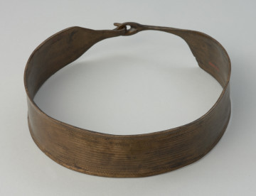 Naszyjnik kołnierzowaty z cienkiej brązowej blachy. - Ujęcie z przodu. Naszyjnik kołnierzowaty z cienkiej brązowej blachy zdobionej żłobkowaniami i delikatnymi zygzakami. Posiada zapięcie w formie haczyka.