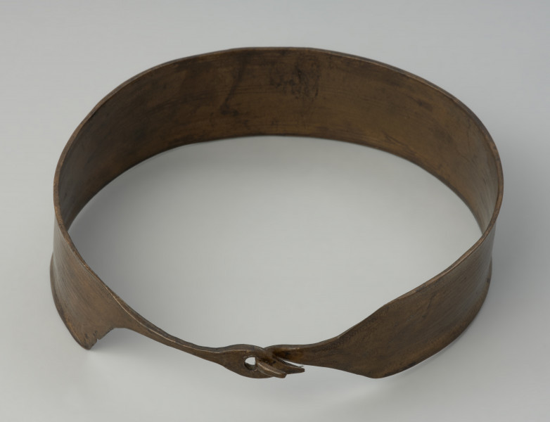 Naszyjnik kołnierzowaty z cienkiej brązowej blachy. - Ujęcie z tyłu. Naszyjnik kołnierzowaty z cienkiej brązowej blachy zdobionej żłobkowaniami i delikatnymi zygzakami. Posiada zapięcie w formie haczyka.