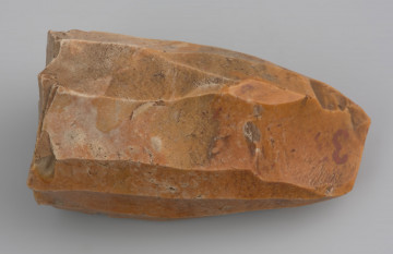 rdzeń wiórowy stożkowaty - ujęcie z przodu; Rdzeń stożkowaty o dookolnej odłupni i świeżonej pięcie. Odłupnia ma 12 negatywów po długich, prostych wiórach odbijanych pośrednikiem. Wykonany z krzemienia dobrej jakości. Pokryty jest czerwono-pomarańczową patyną wskazującą na zaleganie w środowisku o dużej zawartości żelaza.