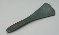 siekierka z podniesionymi brzegami typu Wrocław-Szczytniki - Ujęcie z góry tyłu siekierki. Smukła siekierka z nieco podniesionymi brzegami wykonana z brązu charakteryzuje się wąskim, długim obuchem przechodzącym w rozszerzone, trapezowate ostrze. Zabytek pokrywa zielona patyna.