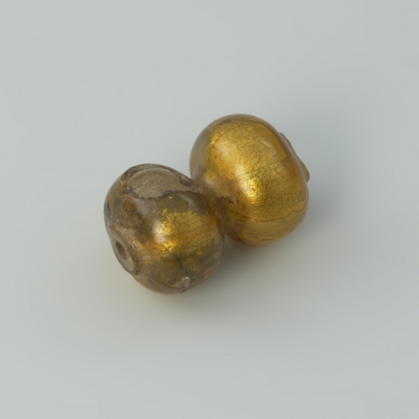 paciorek , biżuteria - Ujęcie przodu paciorka skosem w lewą stronę. Paciorek szklany dwusegmentowy zdobiony złotą folią.