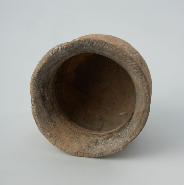 Naczynie gliniane - Ujęcie wnętrza; Przysadzisty puchar o szerokim wylewie, zdobiony na szyjce czterema dookolnymi rzędami ukośnych, podłużnych odcisków, które tworzą pasma złożone z dwóch szeregów odcisków układających się w motyw rybich ości. Ukośnymi nacięciami jest zdobiona także krawędź wylewu.