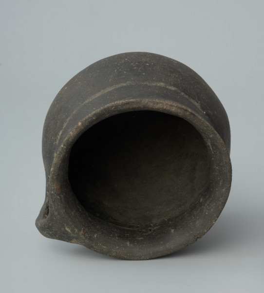 Ujęcie z góry. Niewielka brunatna waza gliniana o wygładzanej powierzchni.