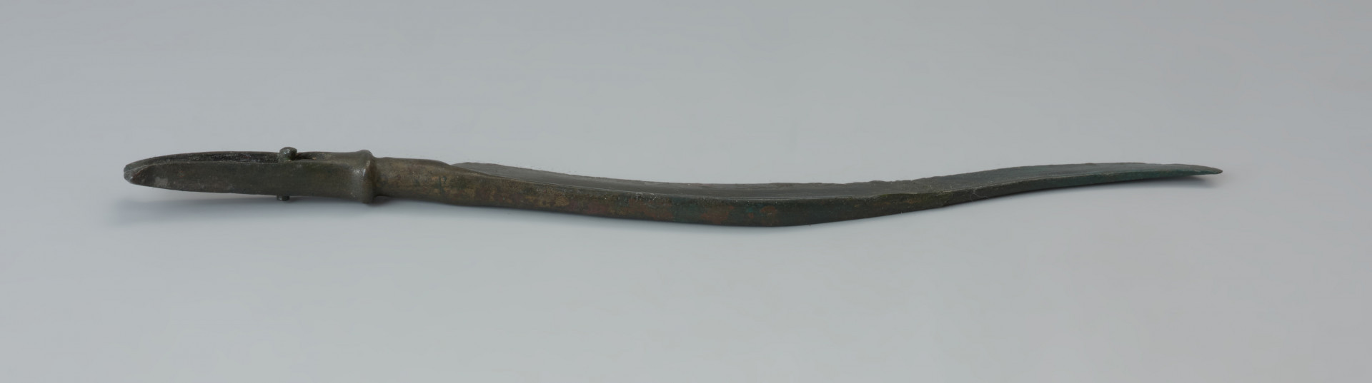 Nóż typu Pfatten - Ujęcie noża w pionie. Długi nóż wykonany z brązu ma smukłe esowato wygięte ostrze i wyraźnie zaznaczony tylec, przechodzący w sztabę do osadzania na niej rękojeści. Podstawa sztaby jest wyraźnie pogrubiona, jej szczyt natomisat uszkodzony. Profilowanie jej pozostałej części uzyskano poprzez charakterystyczne podniesienie brzegów. Przy podstawie zachował się niewielki nit służący do przytwierdzania rękojeści. Na zakończeniach po obu stronach sztaby widnieją dwa skrzydełka.