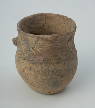 Naczynie gliniane - Ujęcie przodu; Puchar z niewielkim, czworokątnym czopem (uchwytem), zdobiony na szyjce pasmem odcisków sznura, złożonym z 11 regularnych linii. Zrekonstruowany, uzupełniany gipsem barwionym