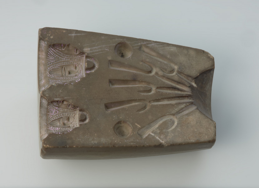 Forma odlewnicza - Ujęcie w poziomie wąskim elementem w prawo.  Jedna część dwudzielnej, kamiennej formy odlewniczej z wizerunkami brodatych twarzy. Wykonano ją ze steatytu zwanego też słoninowcem lub kamieniem mydlanym, który jest miękki i łatwy w obróbce. Zdaniem odkrywców służyć miała do odlewania haczyków do wędek i ciężarków do sieci. Dzisiaj najczęściej uważa się, że jest to forma do odlewu uchwytów niewielkich zawieszek, tzw. osełkowatych lub dzwoneczków. Uwagę zwracają przede wszystkim zróżnicowane wielkościowo wyobrażenia męskich twarzy o migdałowatym kształcie, z dużymi oczami i obfitym zarostem. Po wykonaniu odlewu uzyskiwano przedmiot z wizerunkiem czterech twarzy, uważany za okucie niewielkiej osełki. Forma jest starannie wykonana i nie ma żadnych śladów użytkowania.