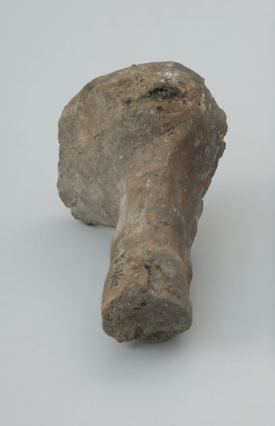 Łyżka odlewnicza - Ujęcie trzonka łyżki. Łyżka odlewnicza wykonana z bardzo mocno spieczonej gliny zachowana fragmentarycznie w postaci części okrągłej, głebokiej nabierki i fragmentu masywnego trzonka