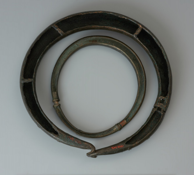 Dwuczęściowy naszyjnik obręczowy - Ujęcie z góry spodu naszyjnika. Zapinany haczykami naszyjnik z brązu, złożony z dwóch obręczy, zdobiony poprzecznym żebrowaniem oraz motywem zygzaka.