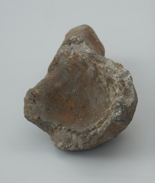 Łyżka odlewnicza - Ujęcie wnętrza łyżki z przodu. Łyżka odlewnicza wykonana z bardzo mocno spieczonej gliny zachowana fragmentarycznie w postaci części okrągłej, głebokiej nabierki i fragmentu masywnego trzonka