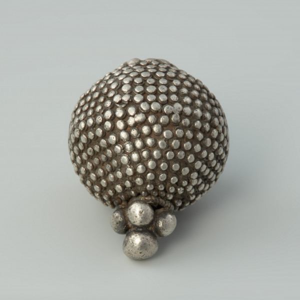 guz, biżuteria, ozdoba - Ujęcie góry w poziomie. Guz srebrny okrągłego kształtu zdobiony granulacją.