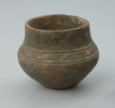 Jasnobrunatne naczynie gliniane o niskiej, przysadzistej formie - Ujęcie z tyłu z prawej strony. Jasnobrunatne naczynie gliniane o niskiej, przysadzistej formie.