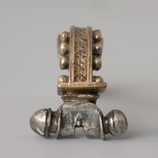 Ujęcie z przodu. Srebrna zapinka z kabłąkiem zdobionym złotymi kulkami.