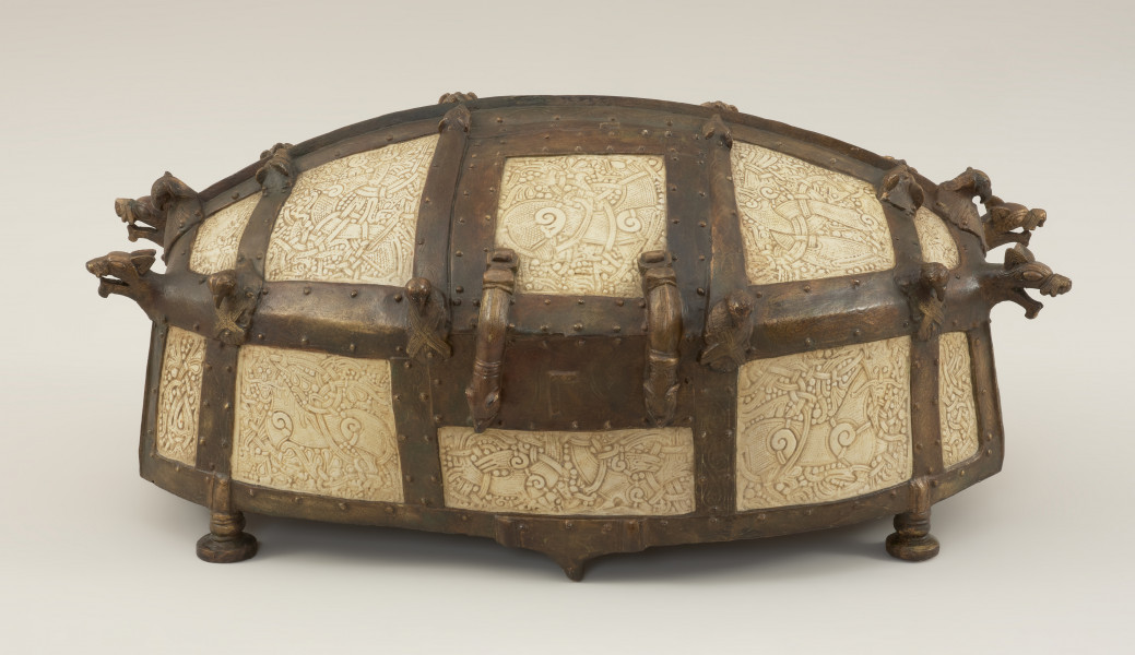 relikwiarz św. Korduli - Ujęcie z przodu. Relikwiarz św. Korduli to owalna szkatuła wykonana z 22 płytek z poroża łosia zdobionych w skandynawskim stylu Mammen, którego głównym motywem był element poskręcanych bestii w towarzystwie wątków roślinnych, stosowany od połowy X do połowy XI wieku. Płytki połączono ze sobą za pomocą pozłacanej miedzianej taśmy, której zwieńczenia mają postać smoczych łbów. Dno relikwiarza wykonano z drewna dębowego, a stało ono na sześciu brązowych nóżkach.