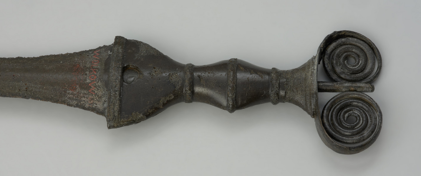 broń, miecz - Ujęcie detalu głowni z przodu. Kompletny miecz z brązu typu antenowego z wąską głownią o odłamanym czubku.