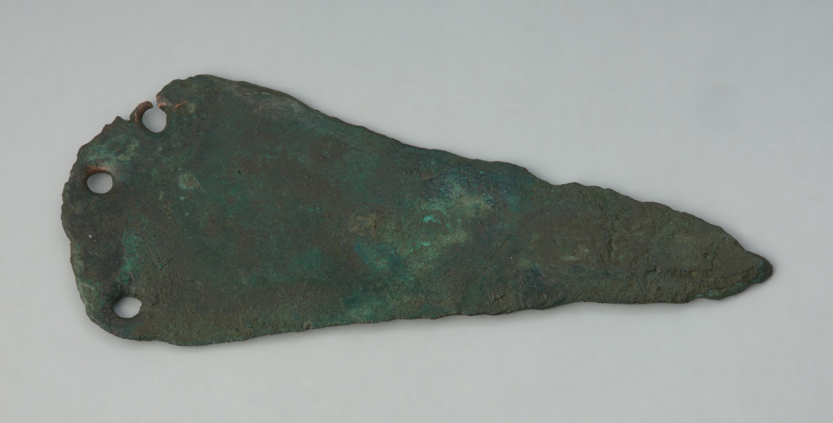 ostrze sztyletu z półkolistym zakończeniem, wariant Mierczyce - Ujęcie z góry przodu głowni. Trójkątna głownia sztyletu z brązu, pokryta zielona patyną, ma półkoliście uformowaną płytkę do przytwierdzania rekojeści, w której znajdują się trzy otwory na nity. Krawędzie ostrza są zniszczone.