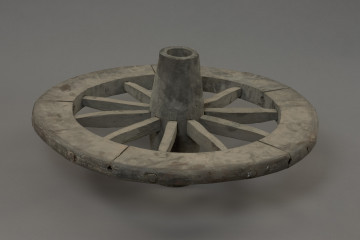 koło - Ujęcie przodu lekko do góry. Replikę koła szprychowego wykonano na podstawie znalezisk z badań wykopaliskowych na Starym Mieście w Kamieniu Pomorskim. Jest produktem kołodzieja, inaczej stelmacha, rzemieślnika zajmującego się wyrobem wozów drewnianych. Poszczególne elementy koła zrobione są z różnych gatunków drewna.