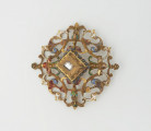 biżuteria, ozdoby - Ujęcie z przodu. Ażurowy klejnot z kołpaka z diamentem, zdobiony barwną emalią.
