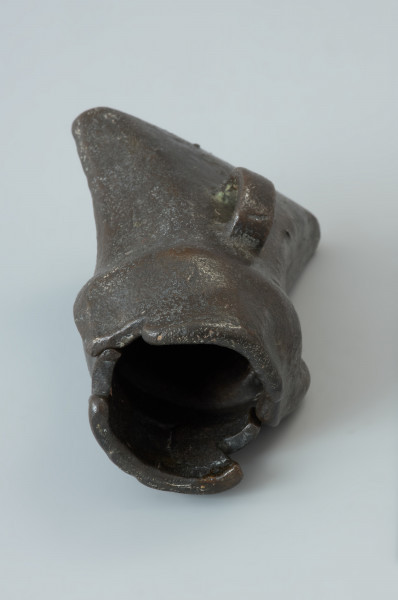 forma odlewnicza; forma muszlowata - Ujęcie w pionie jednego elementu formy od tyłu. Dwuelementowa forma odlewnicza z brązu o brunatnozielonkawej barwie, której kształt wewnętrzny tworzy negatyw siekierki z tulejką i uszkiem. Połówki formy są do siebie dokładnie dopasowane, przy czym jedna zagłębia się lekko w drugiej. Wewnątrz ich korpusów znajdują się niewielkie wypustki w formie czopów, formujących uszko siekierki przy odlewaniu. Na ściankach zewnętrznych każdej połówki znajduje się uchwyt w postaci taśmowatego uszka. Powierzchnie te nie są gładkie a nieco porowate.